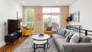 A modern living room with a sofa, two armchairs, a coffee table, and a TV.