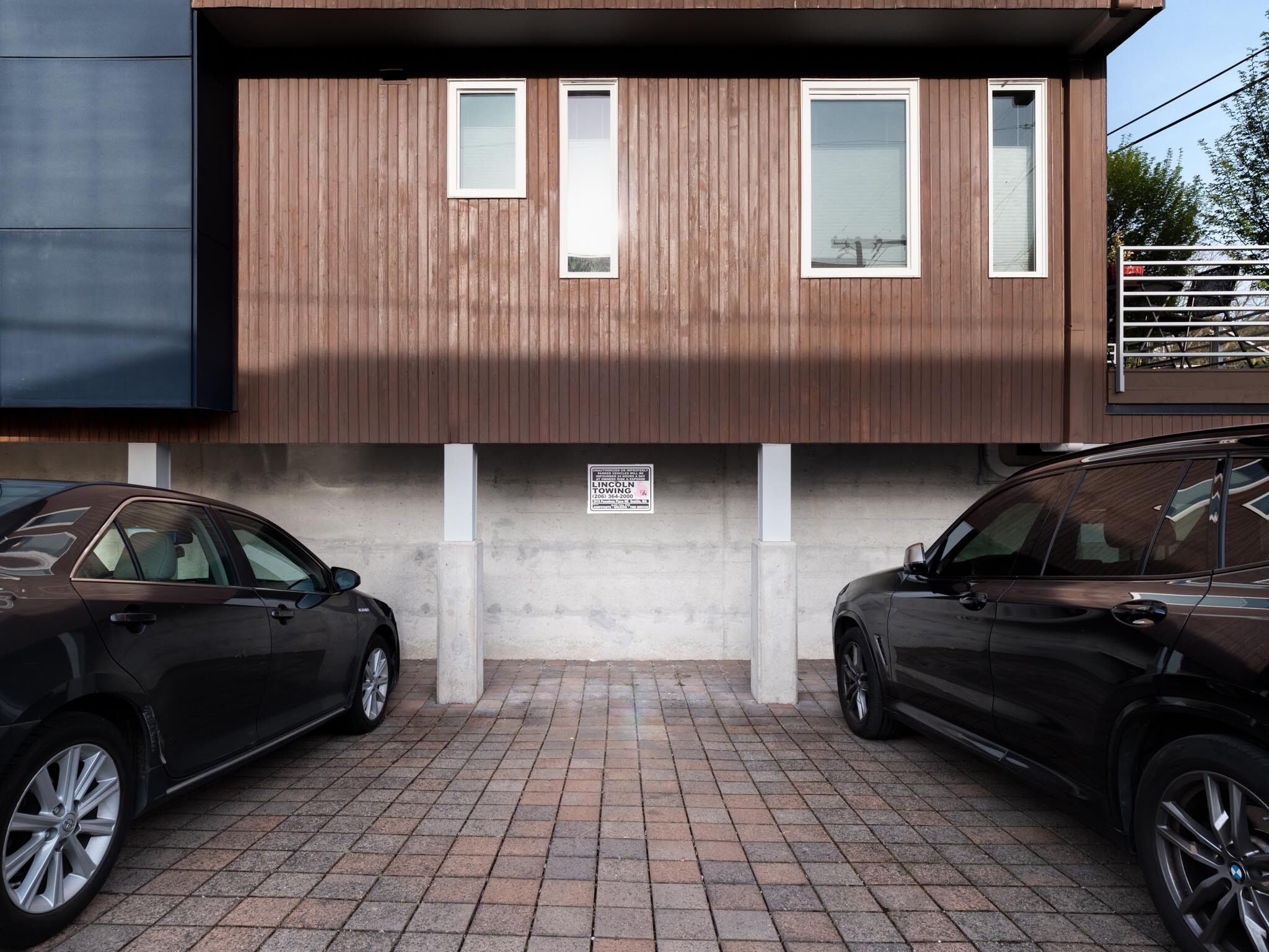 A modern building with a wooden facade and two parked cars.