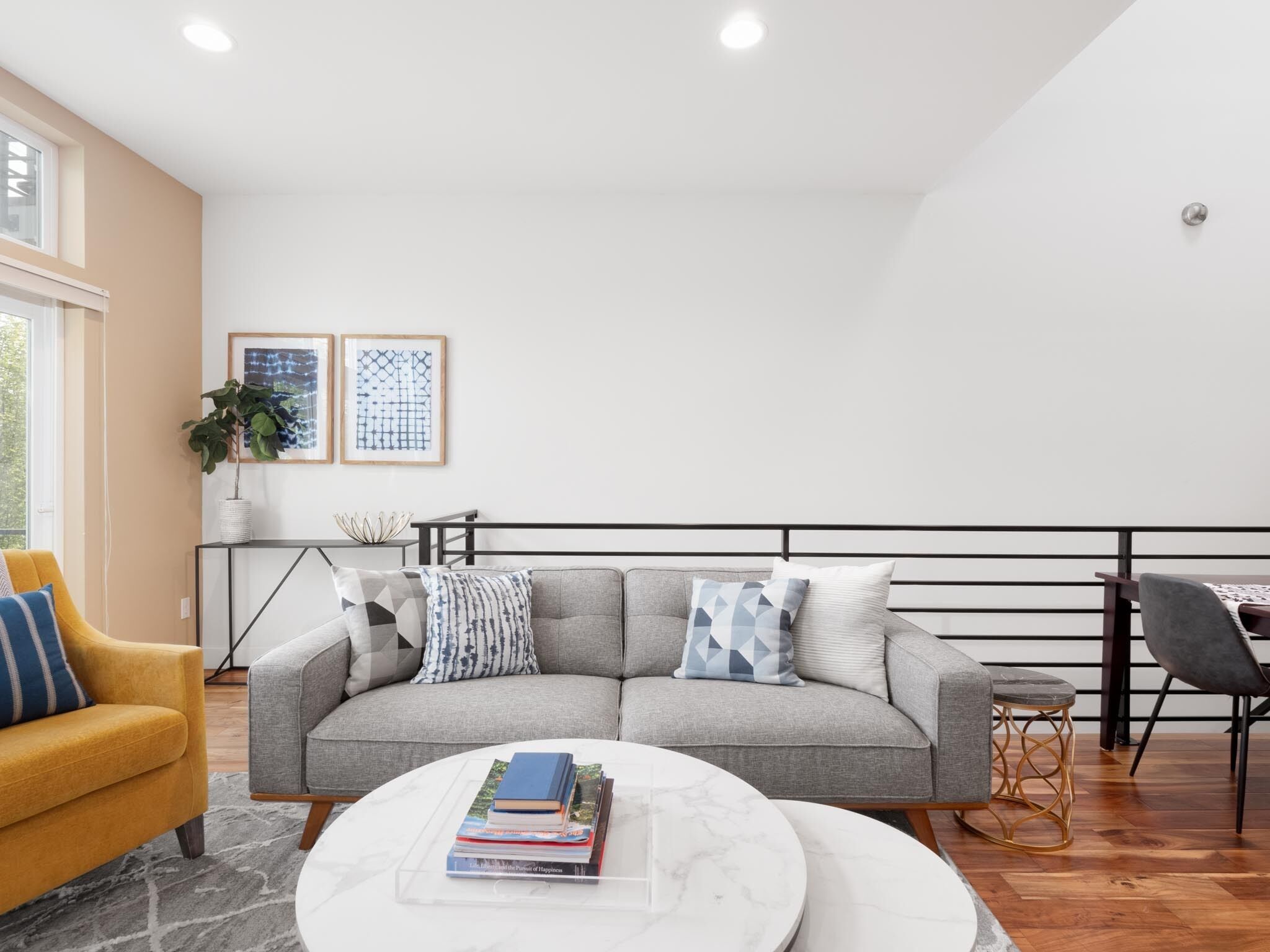 A modern living room with a grey sofa, a yellow armchair, and a white coffee table.
