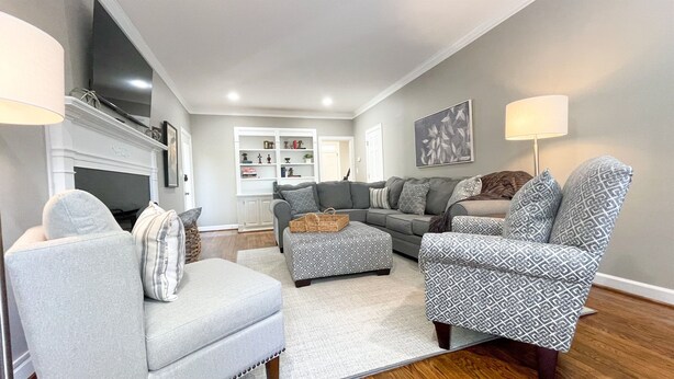 A living room with a sectional sofa, two armchairs, a coffee table, a fireplace, and a bookshelf.