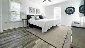 A bedroom with a bed, nightstands, a ceiling fan, and a clock on the wall.
