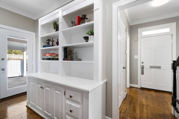 A room with a built-in white shelving unit, wooden flooring, and a white door.