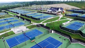 A tennis facility with multiple courts, a covered seating area, and a clubhouse.