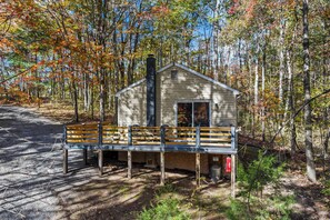 A cabin with a porch and a chimney, surrounded by trees. - A Humble Abode - A Modern Woodsy Retreat (Great Cacapon)