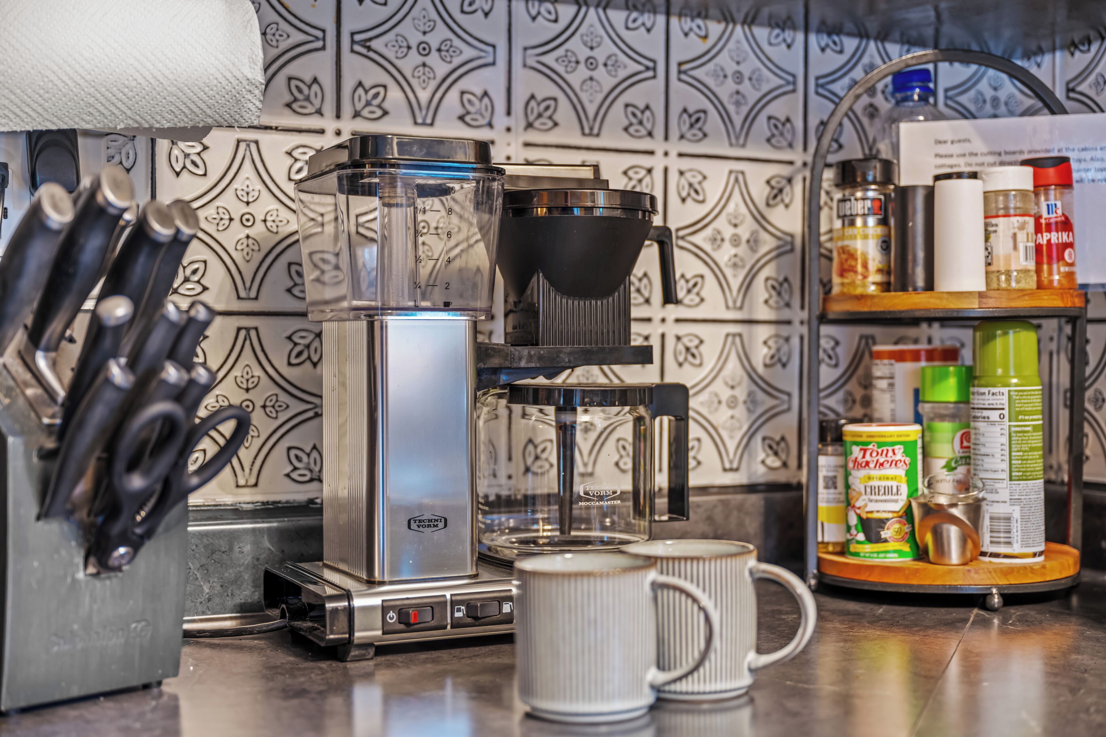 A coffee machine with a grinder, a coffee pot, and a drip coffee maker on a kitchen counter.