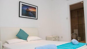 A hotel room with a bed, a nightstand, a wall-mounted picture, and a bathroom visible through an open door. - Nissi Avenue Apartment in Ayia Napa (Ayia Napa)
