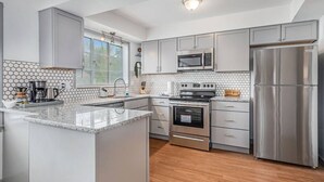 A modern kitchen with grey cabinets, a stainless steel refrigerator, a microwave, and a built-in oven. - The Park & River Chalet - Duplex 2 units (Detroit)