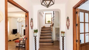 A hallway with wooden flooring, a staircase, and a television in the background. - Rustic house with fireplace and wifi (Nigüelas)