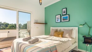 A bedroom with a bed, a nightstand, and a view of the outdoors. - Rooftop Terrace Apartment - Beach House Clerigo by Lisbeyond (Aljezur)