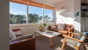 A modern living room with a large window, a sofa, a coffee table, and a floor lamp. - Rooftop Terrace Apartment - Beach House Clerigo by Lisbeyond (Aljezur)