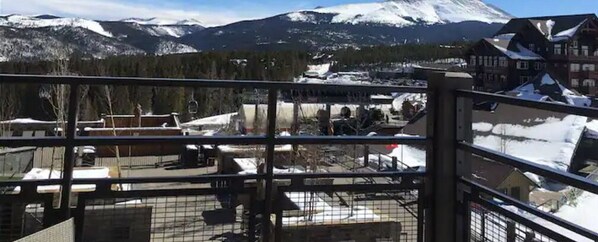 A mountain view with snow-covered peaks, a ski lift, and buildings in the foreground.