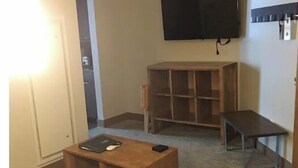 A living room with a wooden coffee table, a sofa, a TV mounted on the wall, and a bookshelf. - Grand Colorado 8,2BR Suite,sleeps8; Ski In/Ski Out (Breckenridge)