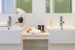 A modern bathroom with two sinks, a potted orchid, and toiletries on the counter.