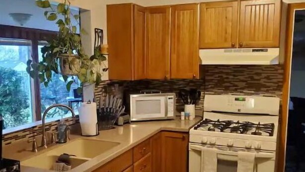 A kitchen with wooden cabinets, a microwave, a stove, and a sink.