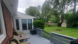 A covered patio with a seating area, a small garden, and a wooden fence.