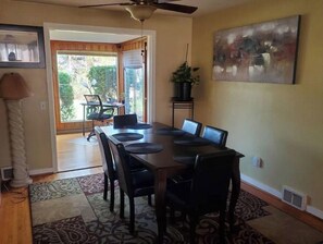 A dining area with a long table, black chairs, and a ceiling fan.