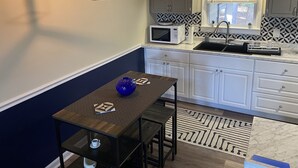 A compact kitchen with white cabinets, a black countertop, a microwave, a sink, and a hanging light fixture. - Marines peaceful retreat, The Spiral @ AbbeyAcres Near Beach with Washer & Dryer (Holly Ridge)