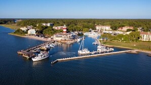 A coastal marina with boats docked, a lighthouse, and buildings along the shore. - Spacious Condo in the heart of Harbor Town! (Hilton Head Island, USA)