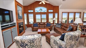 A spacious living room with a large television, leather sofas, and a view of the outdoors. - Oceanside, 7 BRS, Private Pool, Hot Tub, Rec Room, OS1A, Corolla Horizons (Corolla)