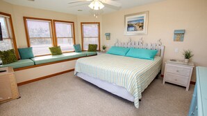A bedroom with a bed, a window seat with cushions, a nightstand, and a framed picture on the wall. - Oceanside, 7 BRS, Private Pool, Hot Tub, Rec Room, OS1A, Corolla Horizons (Corolla)