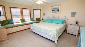 A bedroom with a bed, a window seat with cushions, a nightstand, and a framed picture on the wall. - Oceanside, 7 BRS, Private Pool, Hot Tub, Rec Room, OS1A, Corolla Horizons (Corolla)