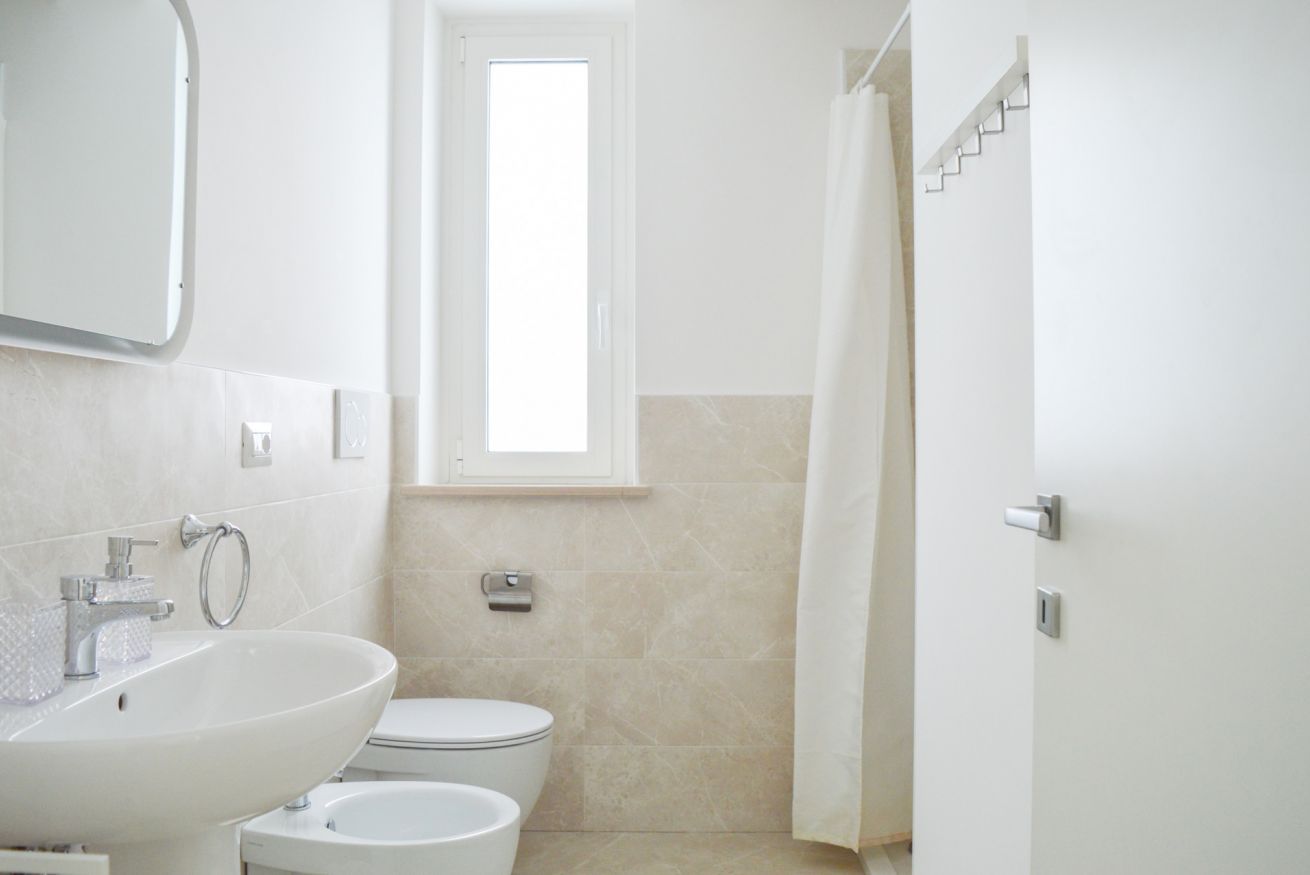 A bathroom with a sink, toilet, and a window.
