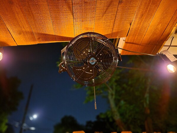 Un ventilador de techo con el logo de la marca a la vista, suspendido de una estructura de techo de madera.