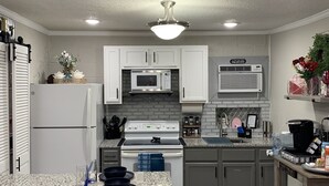 A modern kitchen with white cabinets, a granite countertop, a built-in oven, a microwave, and a coffee station. - PRIVATE Lackland Hideout /Rodeo/ Riverwalk 5.9 mi /Trails/Riverside Golf ⛳️.  (San Antonio)