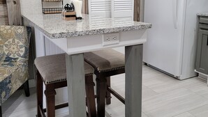 A kitchen with a white refrigerator, a wooden table with a white countertop, and a window with white shutters. - PRIVATE Lackland Hideout /Rodeo/ Riverwalk 5.9 mi /Trails/Riverside Golf ⛳️.  (San Antonio)