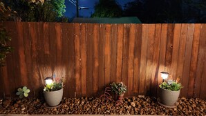 A wooden fence with two potted plants on either side, a bicycle leaning against it, and a street lamp in the background. - PRIVATE Lackland Hideout /Rodeo/ Riverwalk 5.9 mi /Trails/Riverside Golf ⛳️.  (San Antonio)