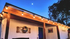 A cozy outdoor seating area with a wooden pergola, string lights, and a wreath on the wall. - PRIVATE Lackland Hideout /Rodeo/ Riverwalk 5.9 mi /Trails/Riverside Golf ⛳️.  (San Antonio)