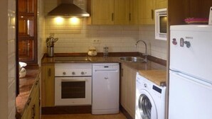 Una cucina compatta con piano cottura, forno, lavatrice e lavandino.
