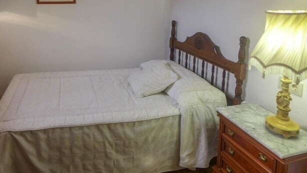 Una camera da letto con un letto singolo, un comodino e una lampada a muro.