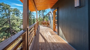 Une terrasse en bois avec une rambarde, une porte et une fenêtre.