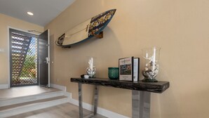 Ein Empfangsbereich mit einer Rezeption, einer Surfbrett-Dekoration und einem gerahmten Zertifikat an der Wand.