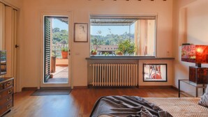 Une chambre à coucher comprenant un lit, un radiateur, une fenêtre donnant sur un paysage agréable et une porte menant à un espace extérieur.
