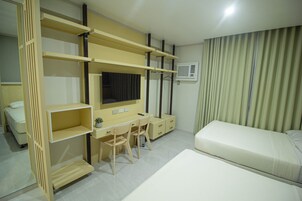 A hotel room with a bed, a desk with a chair, a TV, and a wardrobe.
