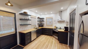 Une cuisine moderne avec des meubles noirs, des plans de travail en bois et des appareils électroménagers en acier inoxydable.