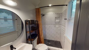 Une salle de bain comprenant des toilettes, un lavabo et un espace douche.