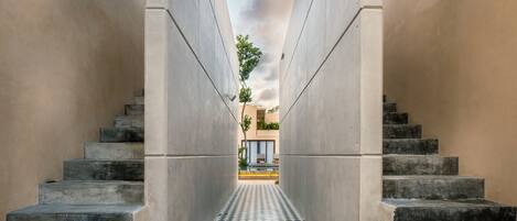 A corridor with a checkered floor leading to a building with a glass facade.
