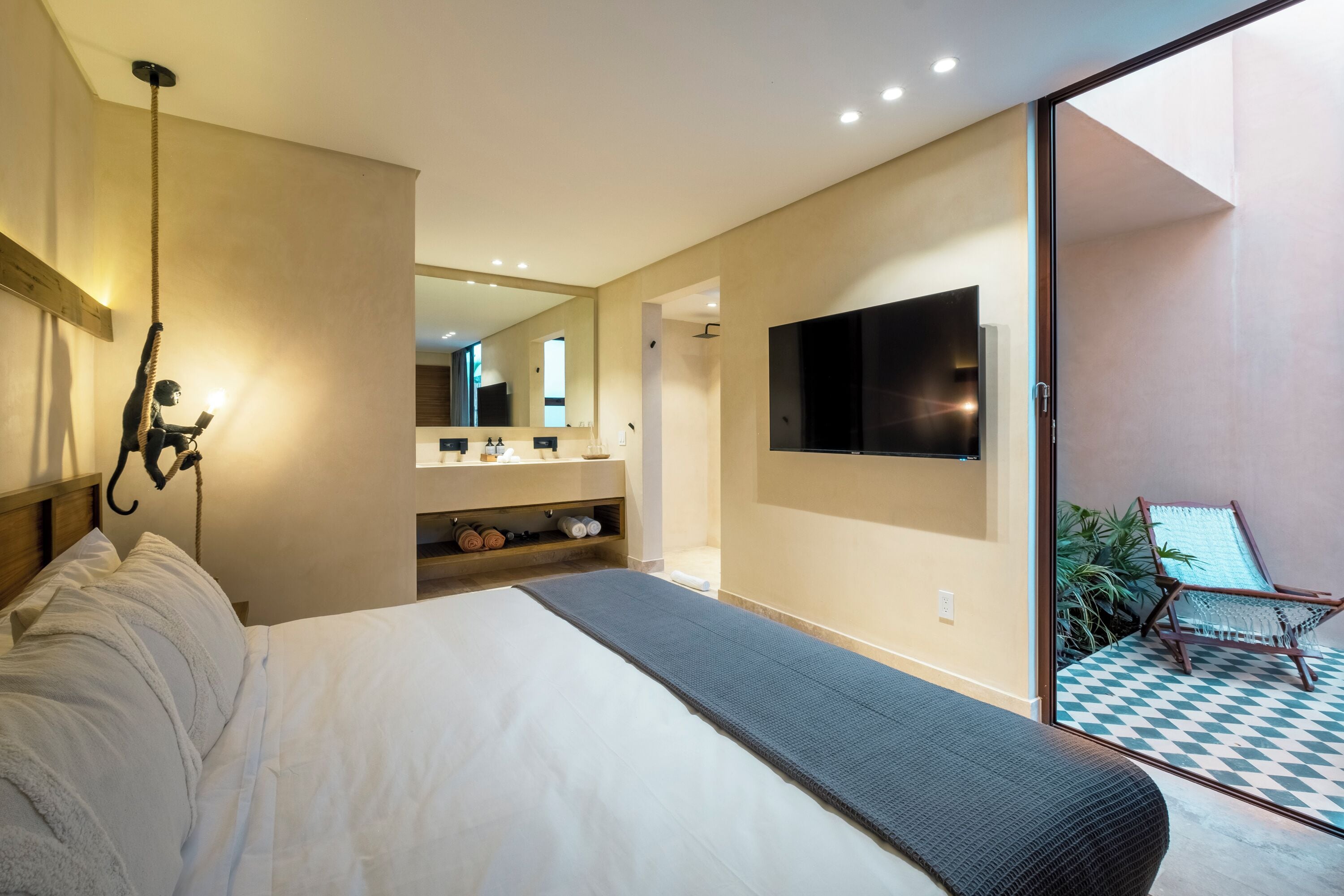 Quarto moderno com uma cama grande, televisão na parede e varanda com piso xadrez.