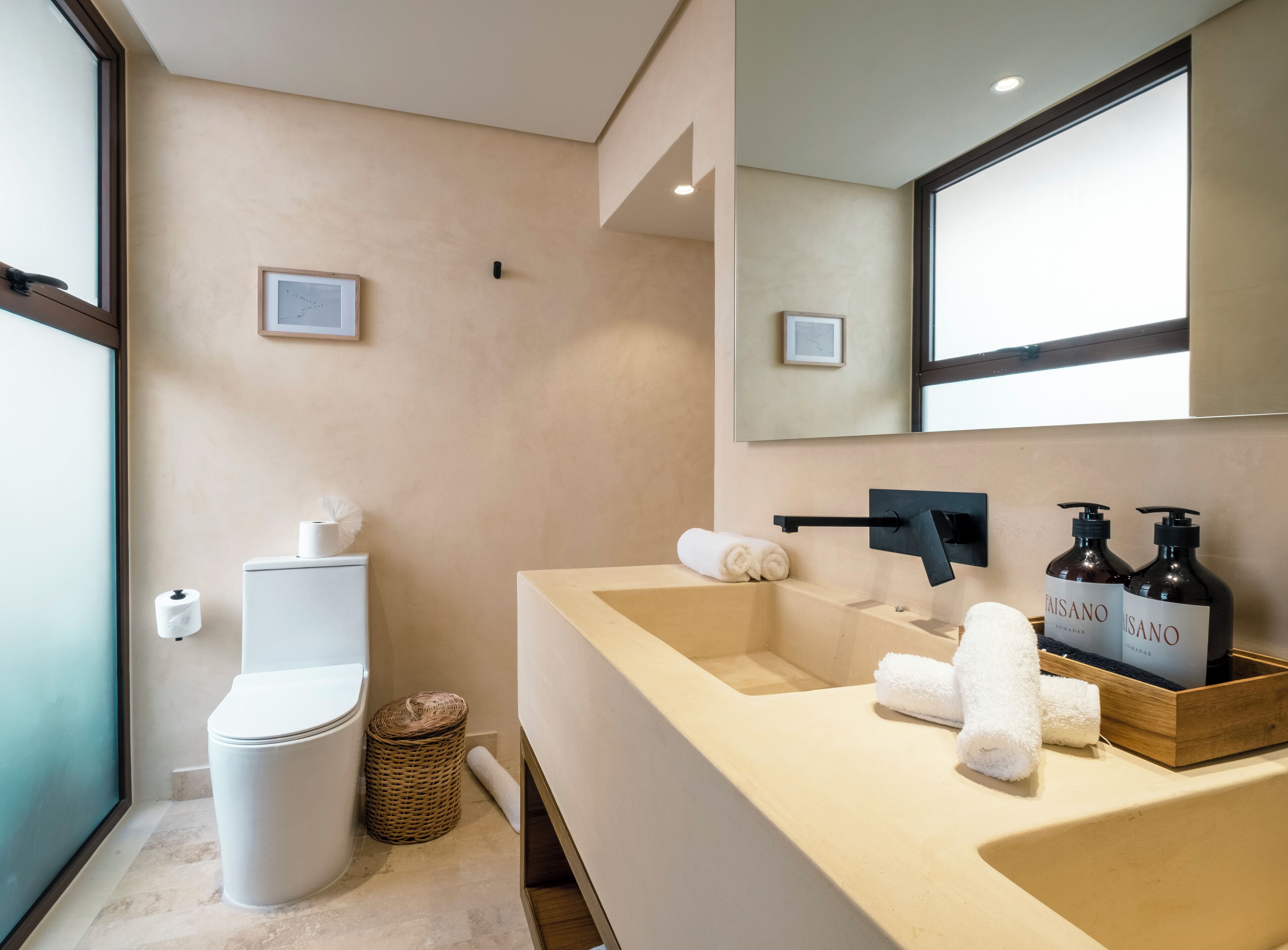 A modern bathroom with a toilet, sink, and mirror.