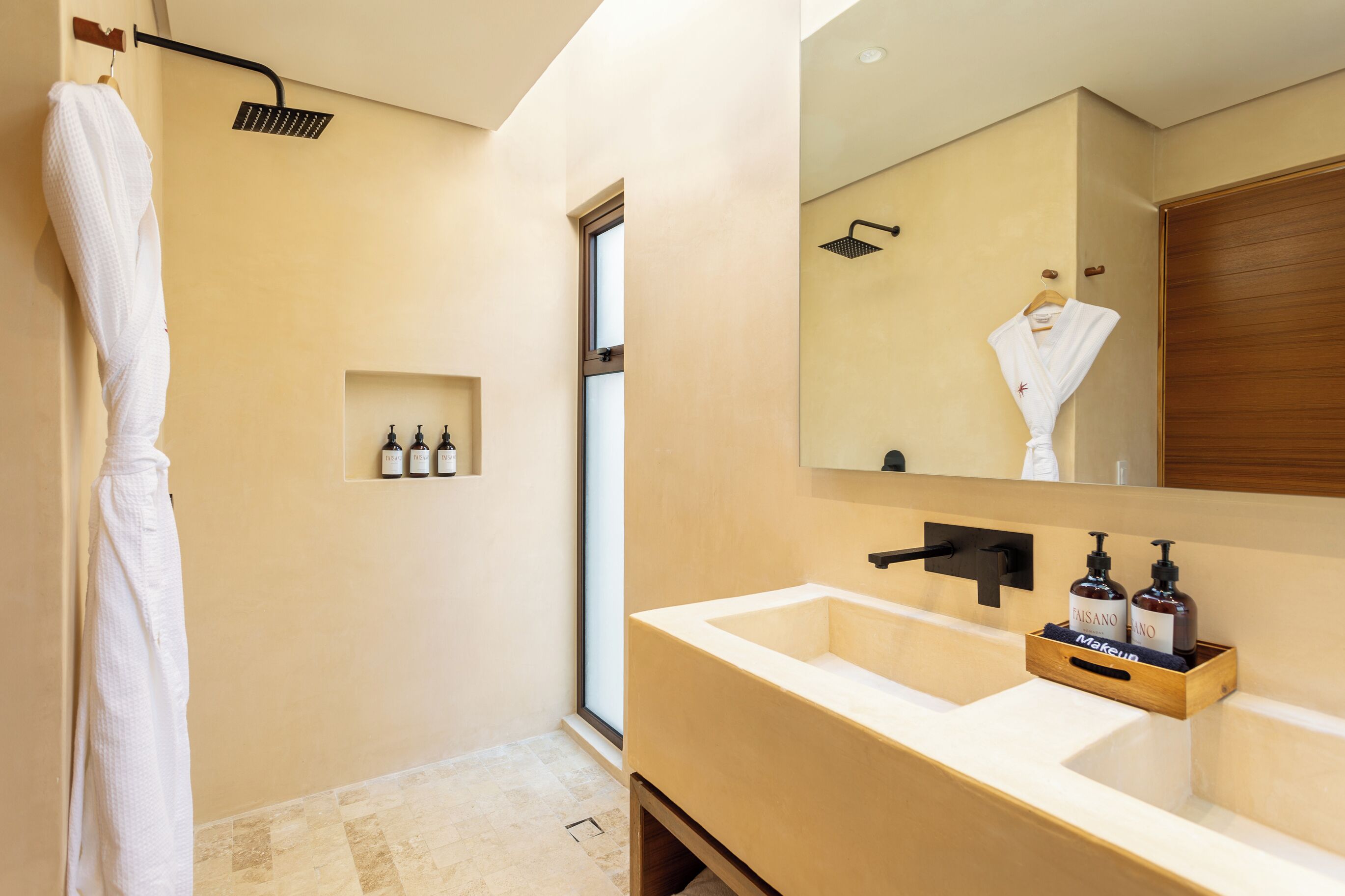 A modern bathroom with a large mirror, a beige sink, and a shower with a handheld showerhead.