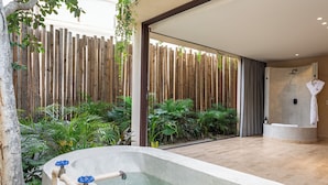 A modern bathroom with a bathtub, shower, and a wooden fence.