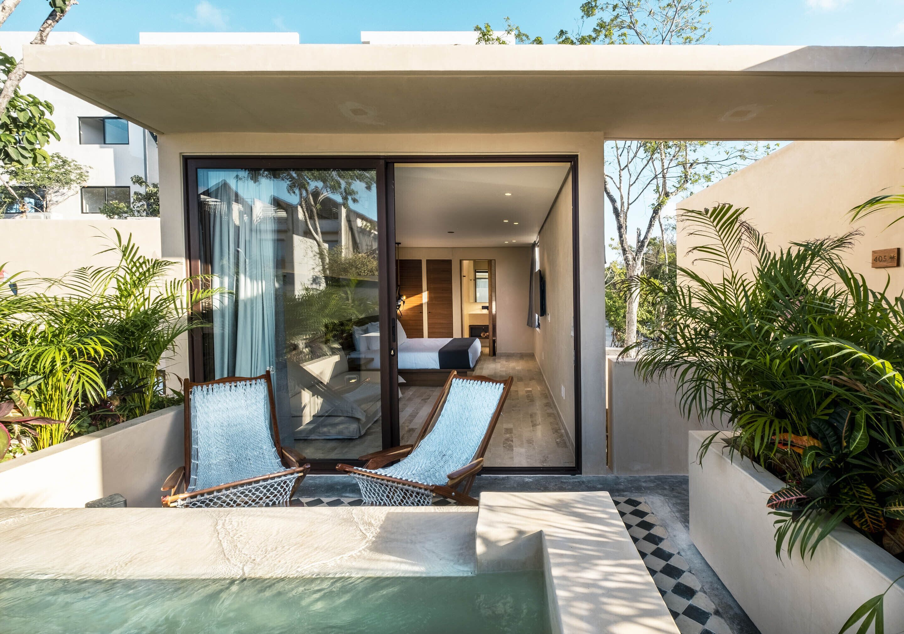 A modern outdoor pool area with two lounge chairs and a small pool.