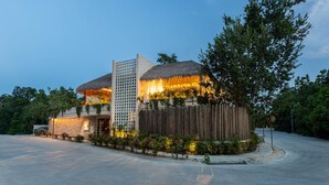 A modern building with a thatched roof, stone walls, and a wooden fence.