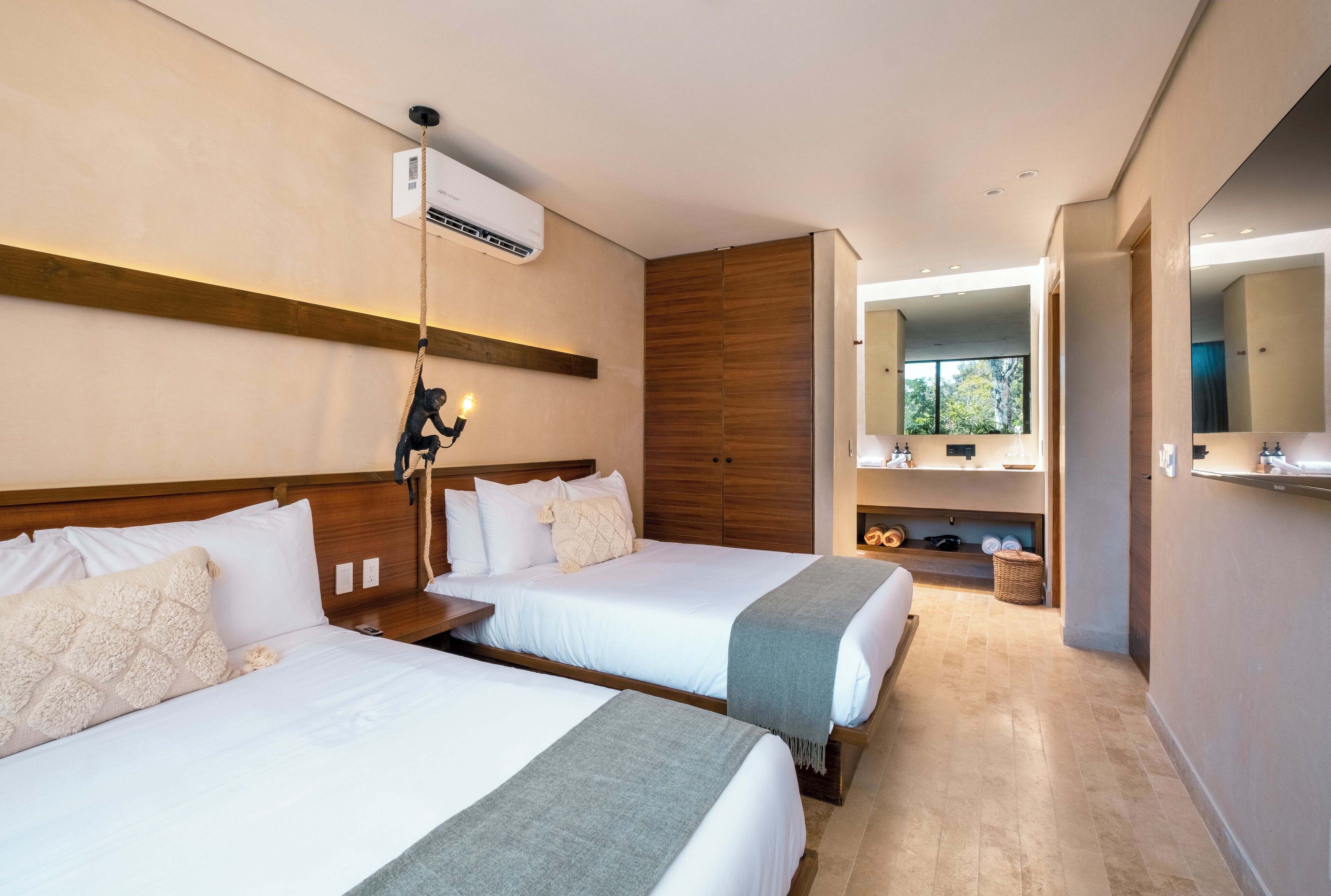 Ein Hotelzimmer mit zwei Betten, einem Holzkopfende, einem großen Spiegel und Blick ins Freie.