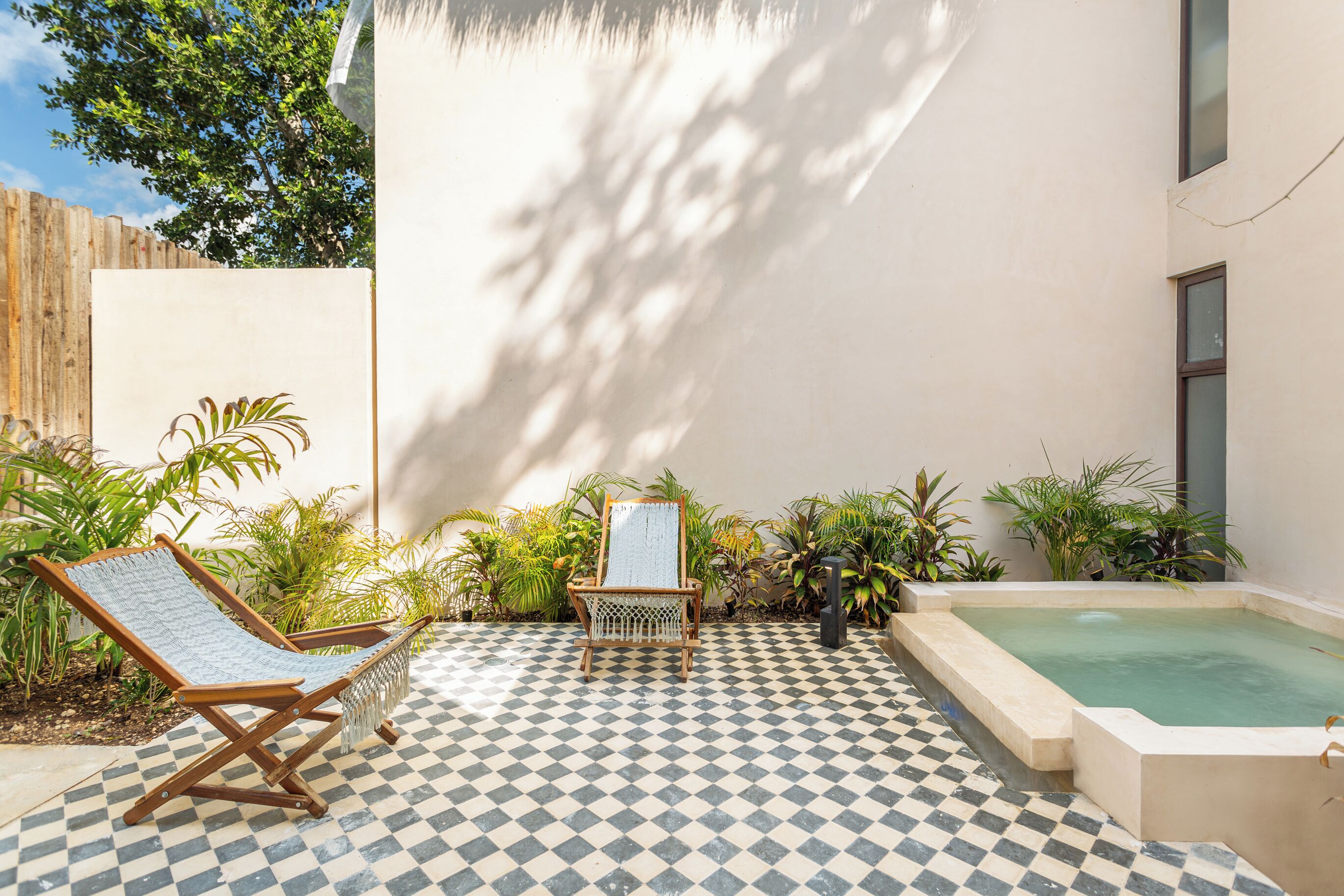 Un espace extérieur à carreaux comprenant une piscine, des chaises longues et des plantes en pot.