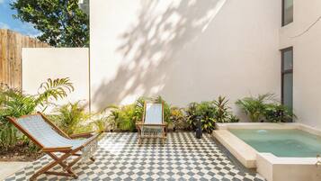 Un espace extérieur à carreaux comprenant une piscine, des chaises longues et des plantes en pot.