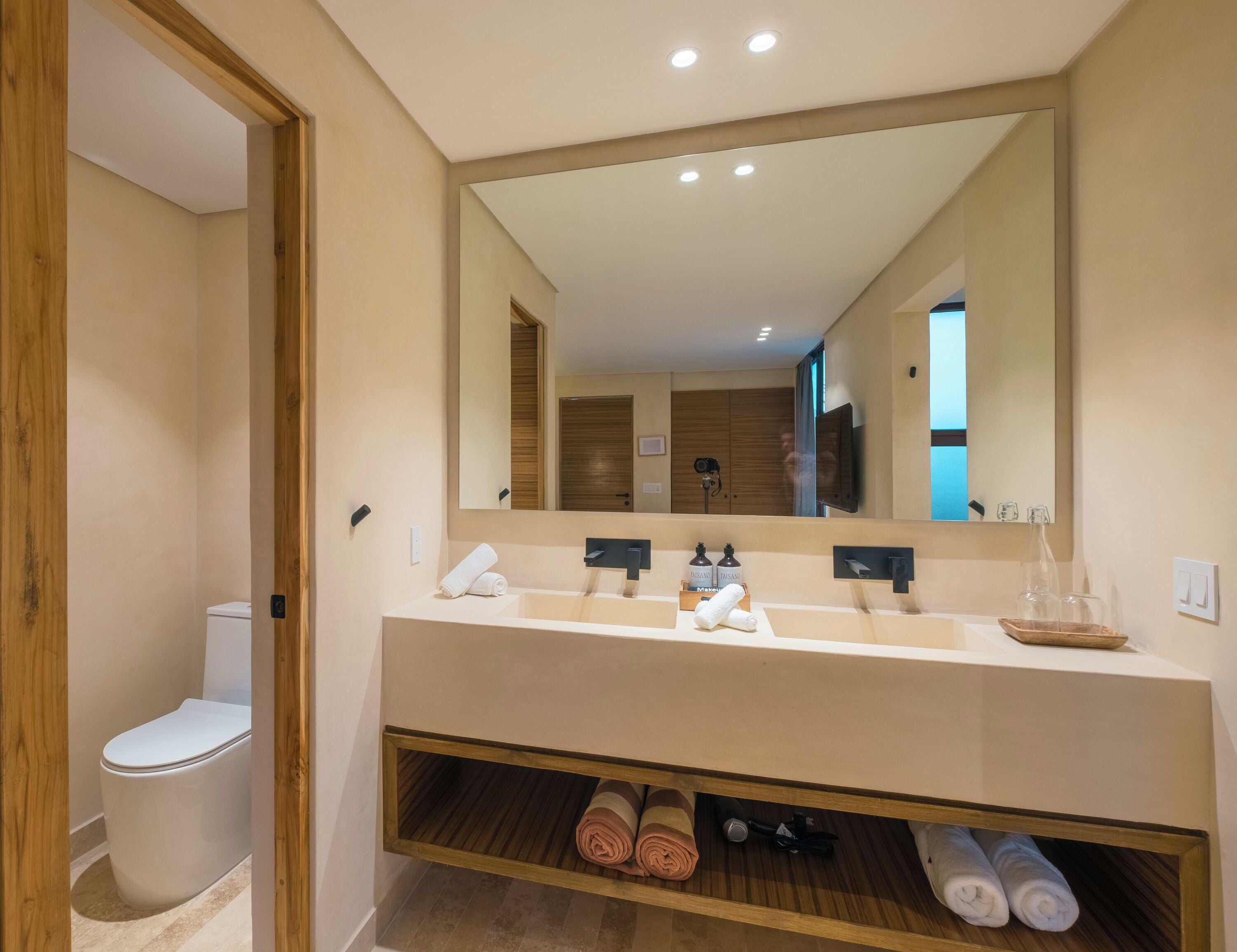 A modern bathroom with a large mirror, a sink, and a toilet.